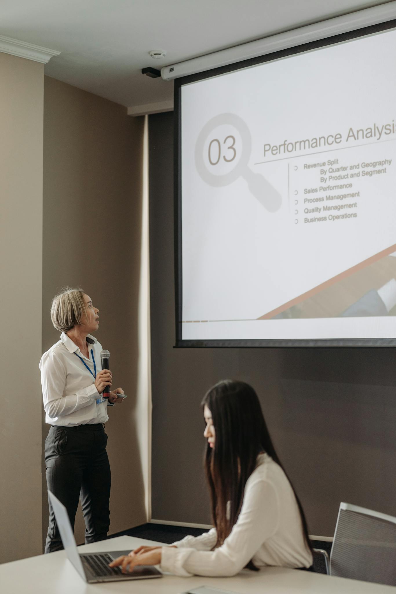 Professional business presentation with women using microphone and projector.